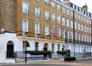 Klasik Regency mimarisi, İngiliz bayrağı ve büyüleyici mevsimlik dekorasyonların yer aldığı Londra caddesindeki bir binanın ön cephesi.