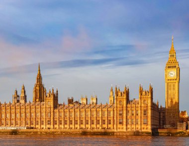 Westminster Sarayı ve Big Ben saat kulesi, Londra ve tarihin bir sembolü olan Thames Nehri 'nin sıcacık güneş ışığıyla yıkandı.
