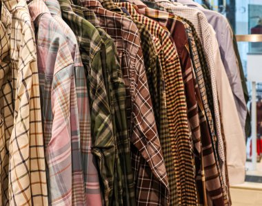 Bir giyim mağazasındaki askılarda satılmaya hazır çeşitli ekose ve kareli fanila gömlekler.