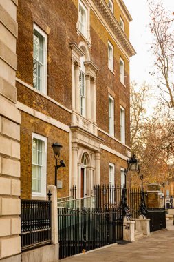 Klasik Gürcü mimari tarzı, sıcak tuğla cephesi, beyaz kuşak pencereleri ve parmaklıklarla süslü bir girişi olan Londra binası.