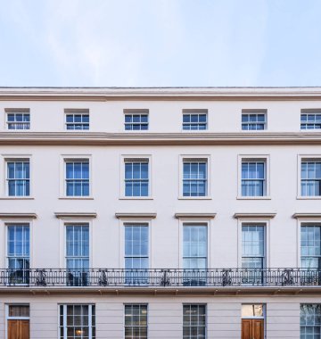 Gürcü terasları, klasik pencereleri ve açık gökyüzünün altında siyah işlenmiş demir bir balkonu olan zarif Londra binası.