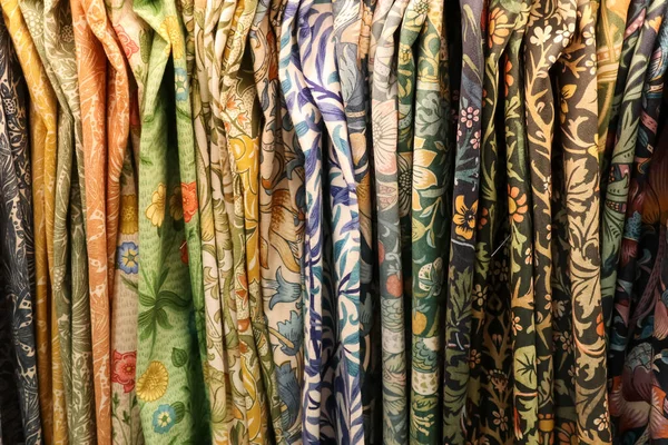 Çeşitli desenli kumaşlar dikey asılıyor, Sanat ve El Sanatları hareketinden esinlenerek karmaşık çiçek ve botanik motifler sunuluyor.