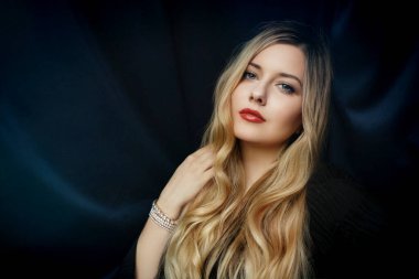 Kırmızı rujlu, sarı dalgalı saçlı, zarif ve modaya uygun, kendine güvenen bir kadın.