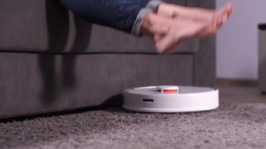 Kadın bacakları çalışan elektrik süpürgesinin üzerine kalkıyor.