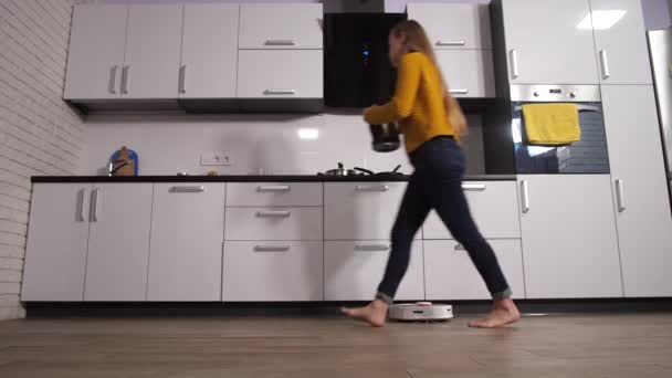 로봇 청소를 하면서 가정 부엌에서 일하는 여자 — 비디오