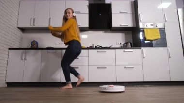 Kadın mutfakta dans ederken robot temizliği yapıyor.