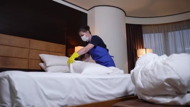 Camarera de hotel en máscara y guantes cambiando ropa de cama — Vídeo de stock