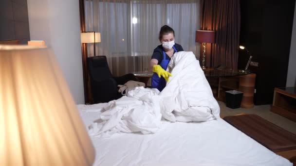 Gemaskerde huishoudster verwijdert duurzaam beddengoed uit bed — Stockvideo