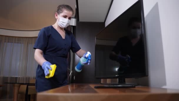 Kvinnlig arbetare rengöring yta nära TV-apparaten i rummet — Stockvideo
