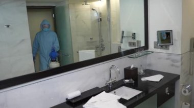 Otel çalışanı covid-19 sırasında banyoyu dezenfekte ediyor.