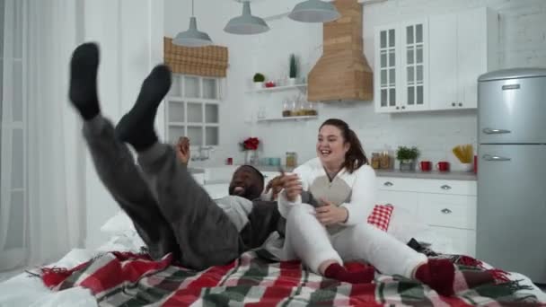Radosna, wielorasowa para zabawiająca się na łóżku — Wideo stockowe