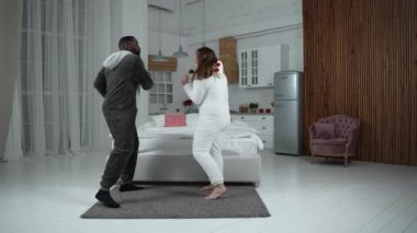 Evde pijamalı neşeli çiftin eğlenceli dansı.