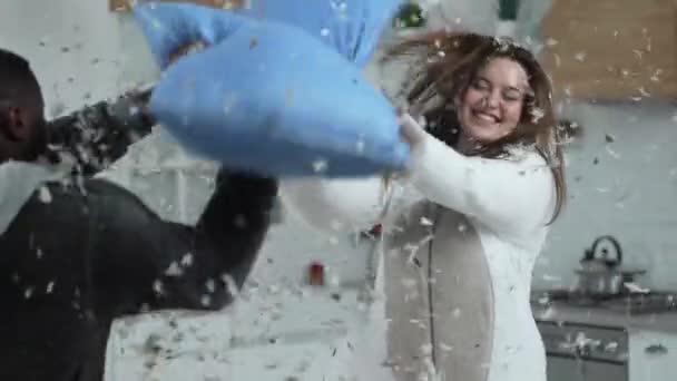 Laughing curvy woman having pillow fight with man — Stock Video