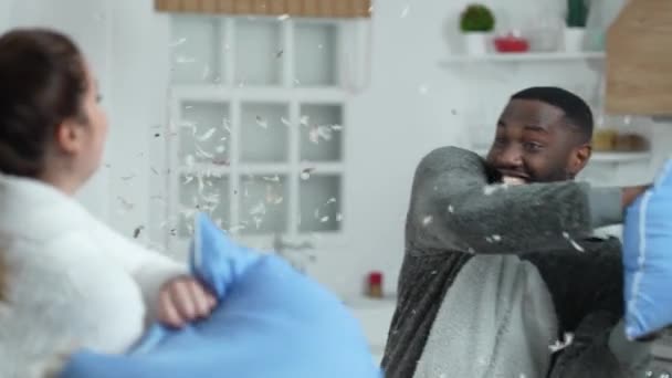 Multiethnisches Paar genießt Kissenschlacht zu Hause — Stockvideo