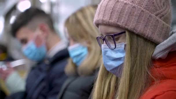 Młodzi ludzie w maskach twarzy jadący metrem — Wideo stockowe