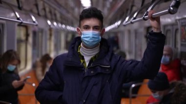 Metroda maskeli ve ceketli bir genç.