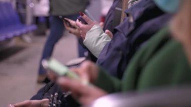 Metroda oturan gençlerin telefonlarıyla meşgul.