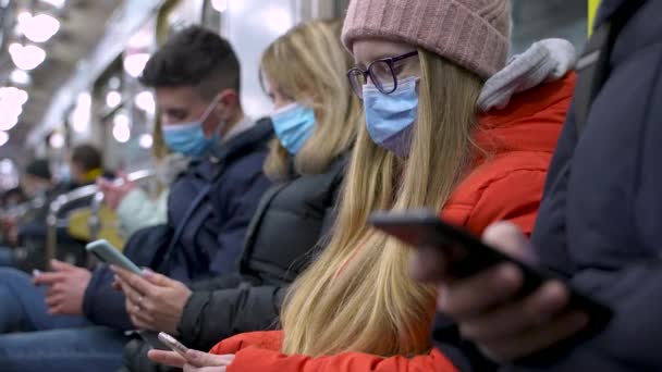 Zamaskowani młodzi ludzie zajęci telefonami w pociągu metra — Wideo stockowe