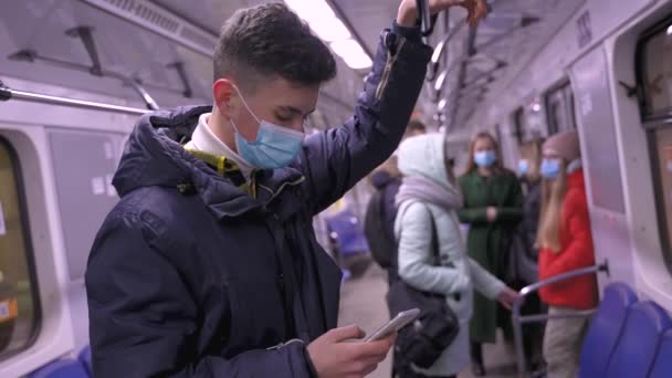 Menino adolescente em máscara médica usando celular no metrô — Vídeo de Stock