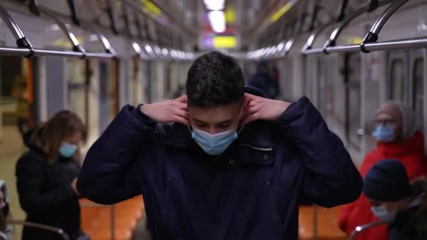 Высокий подросток надевает маску на лицо в поезде метро — стоковое видео