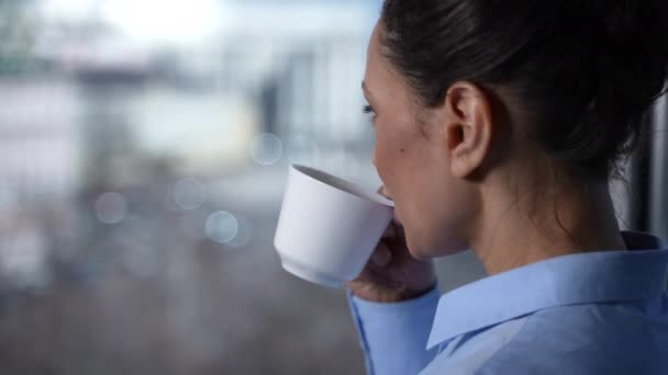 Улыбающееся лицо женщины, пьющей кофе у окна — стоковое видео