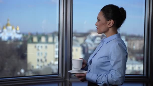 Zelfverzekerde zakenvrouw die koffie drinkt bij het raam — Stockvideo