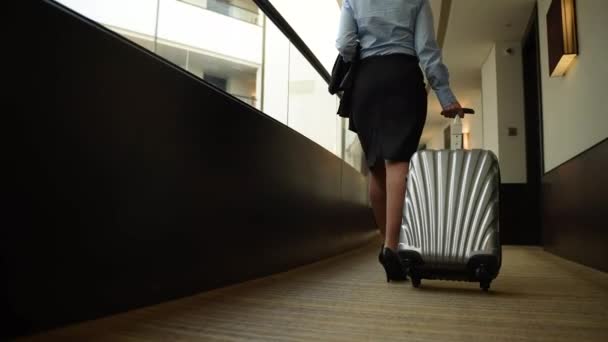 Female with suitcase walking along hotel corridor — Stock Video