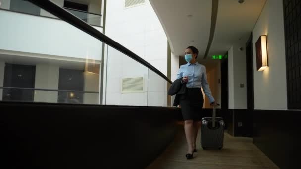 Masked businesswoman walking along hotel corridor — Stock Video