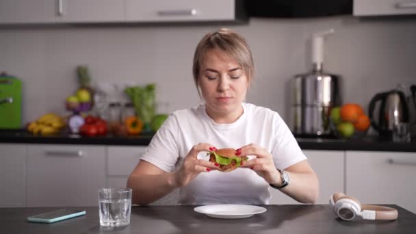 Schlanke Frau weigert sich, Burger in Küche zu essen — Stockvideo