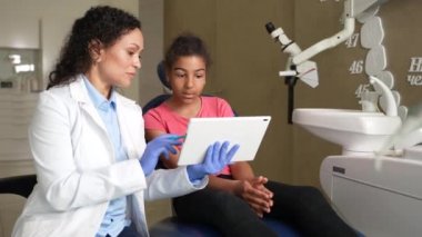 Çocuğa diş röntgeni gösteren pediatrik dişçi