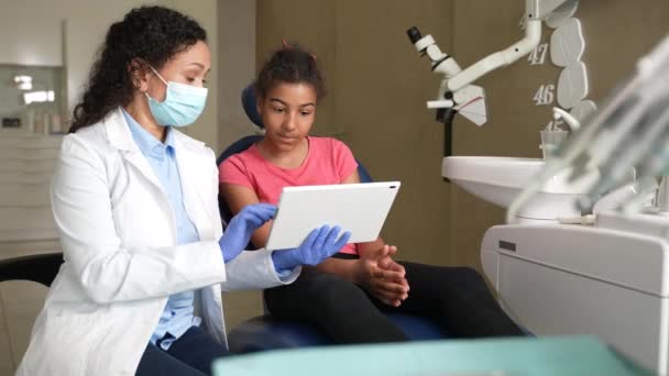 Mujer dentista mostrando radiografía dental a paciente infantil — Vídeos de Stock