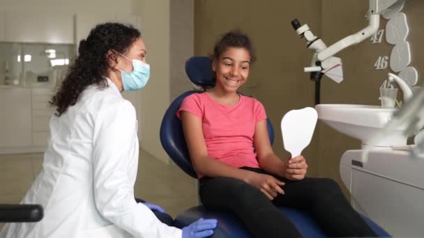 Kudrnatá dívka pacient dívá na zuby v zrcadle — Stock video