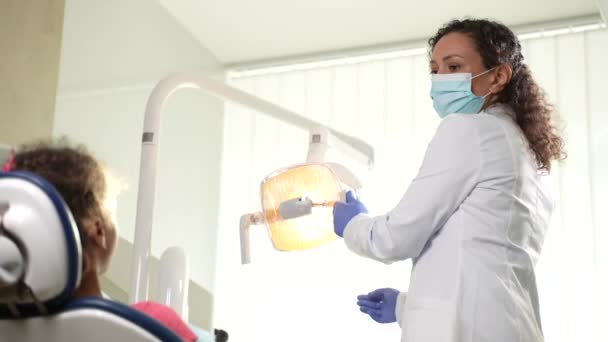 Mujer dentista ajustando la luz en la unidad dental — Vídeos de Stock
