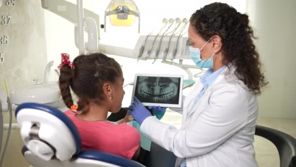 Kadın stomatolog dişçi röntgenini kıza gösteriyor. — Stok video