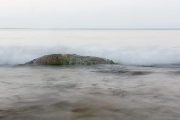 De steen in het zeewater onder de tegemoetkomende Golf — Stockfoto