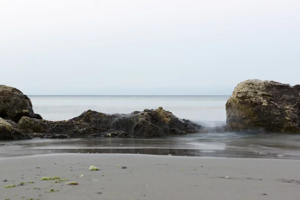 Der Stein im Meerwasser unter der aufkommenden Welle — Stockfoto