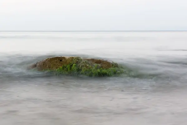 De stenen op het strand onder de binnenkomende golf — Stockfoto