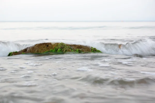 De stenen op het strand onder de binnenkomende golf — Stockfoto