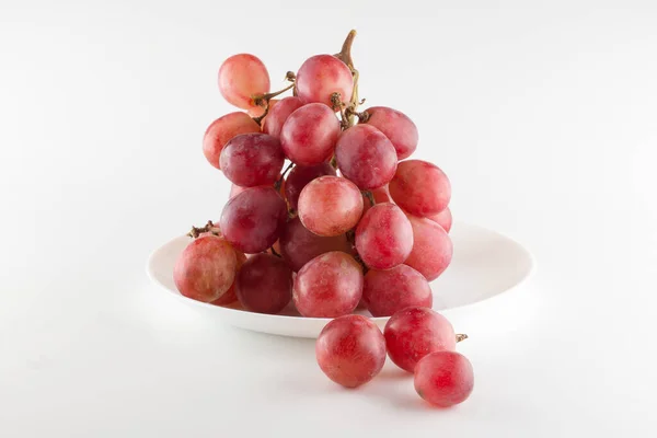 一束新鲜的葡萄放在白背石上的餐盘上 — 图库照片