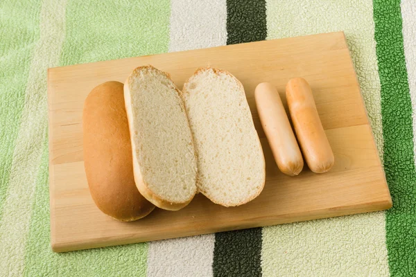Salsiccia e pane si trovano su una tavola — Foto Stock