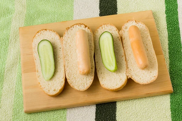 Pølse og brød med agurk på et hakkemat av tre – stockfoto