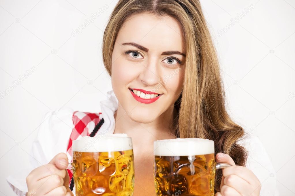 Woman posing in dirndl dress against a white wall.