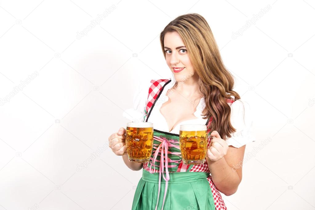 Woman posing in dirndl dress against a white wall.