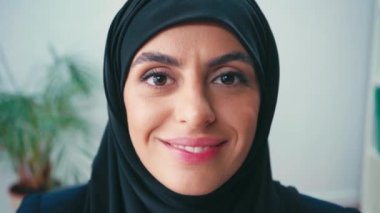 Kameraya gülümseyen Müslüman kadının portresi. 