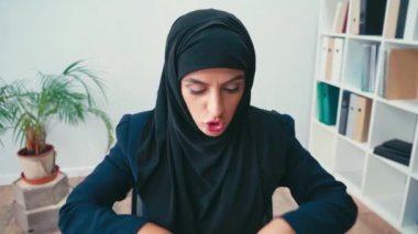 Kızgın Müslüman iş kadını kameraya kağıtları gösteriyor ve kırıştırıyor. 