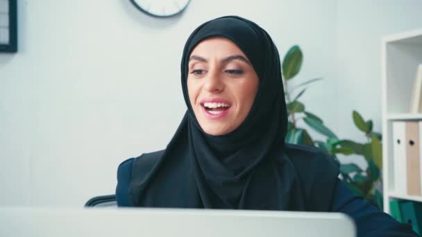 笑顔イスラム教徒のビジネスマン女性持っていますビデオチャット上のラップトップ上でぼやけた前景 — ストック動画