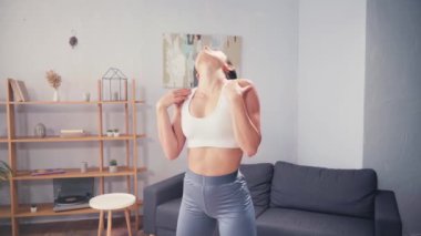 Spor kadını evde antrenman yaparken boynunu ve omuzlarını ısıtıyor. 