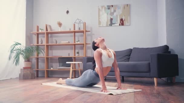 穿着运动服的女人躺在客厅的健身垫上 — 图库视频影像