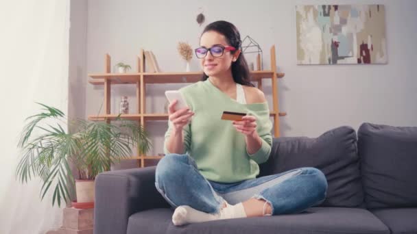 自宅でクレジットカードやスマートフォンを使用して陽気な女性 — ストック動画