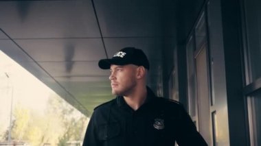 Dışarıdaki binanın yakınında yürüyen ve selamlayan bir polis memuru.